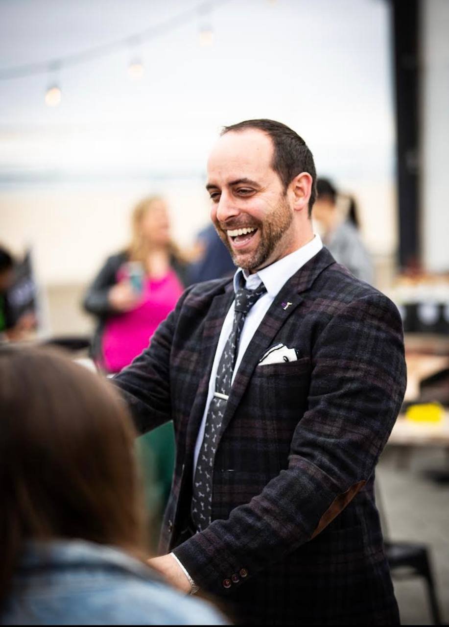 Naz Magic smiling while performing for guests in a suit