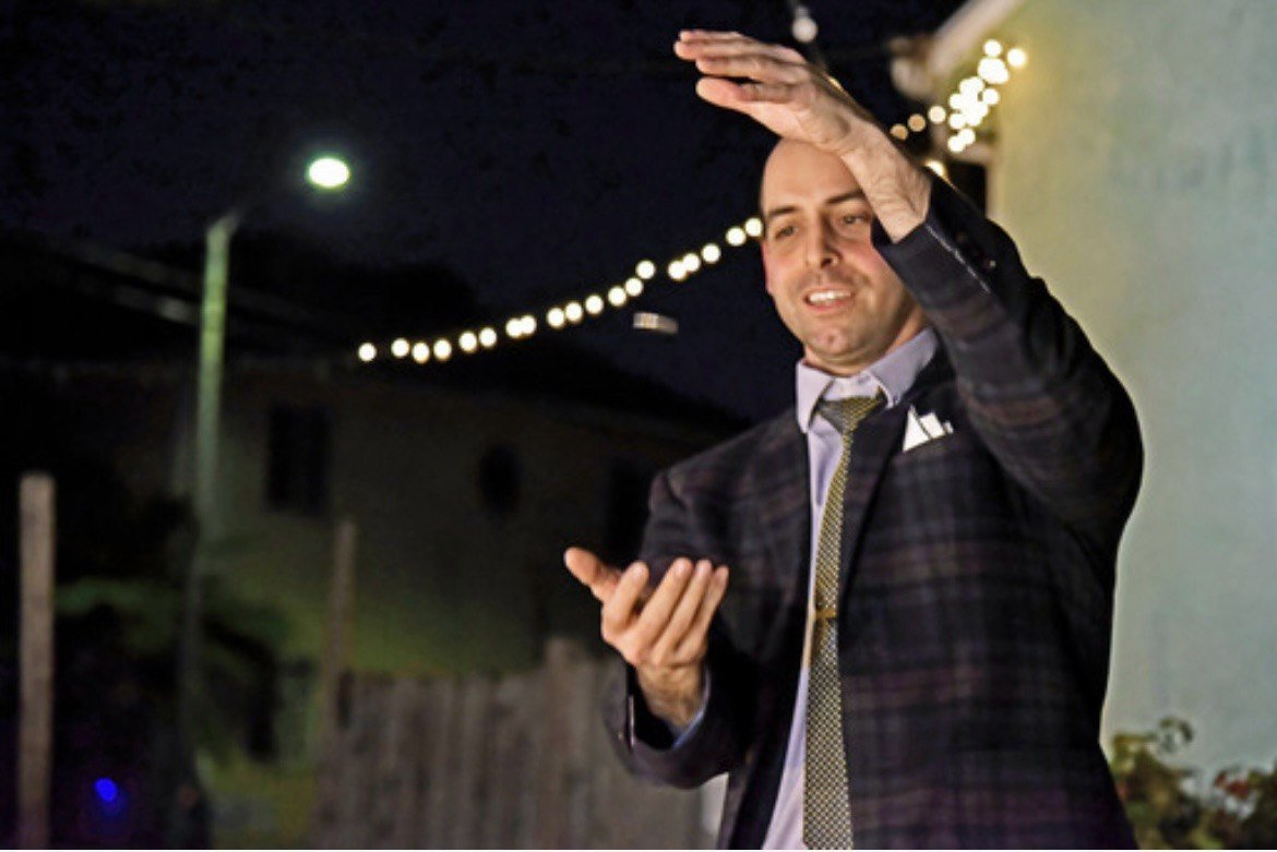 Naz Magic raising a playing card for an audience outdoors at night